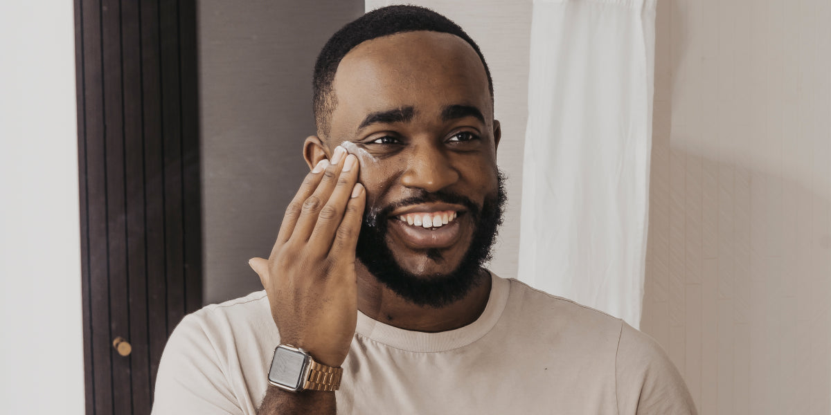 A black man applying an exfoliation cream.