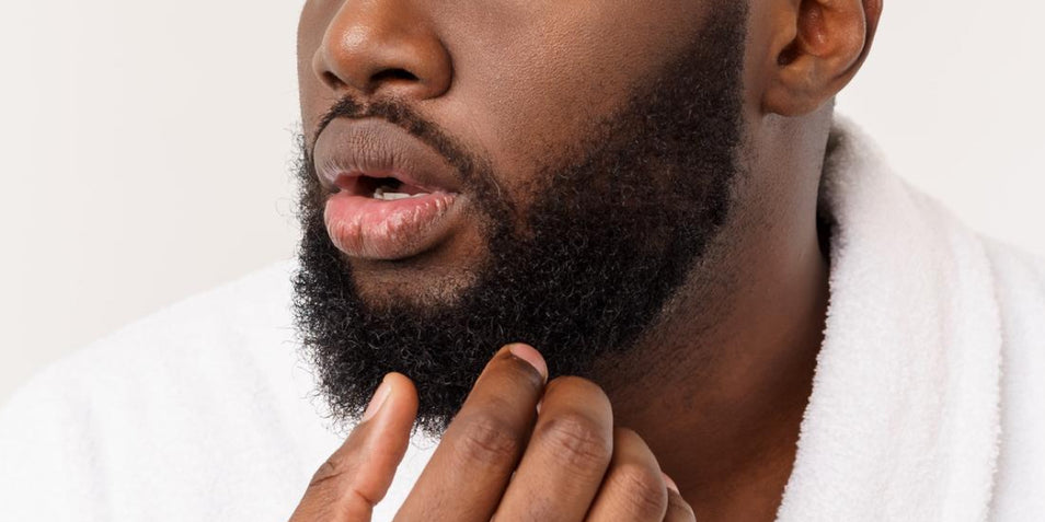 A black man touching his healthy-looking beard.