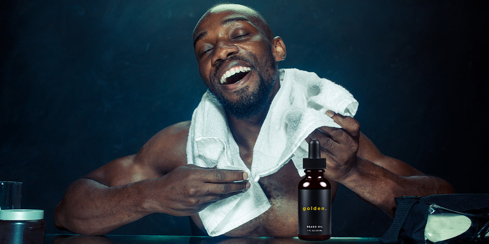 A man happily showing the best beard oil for black men.