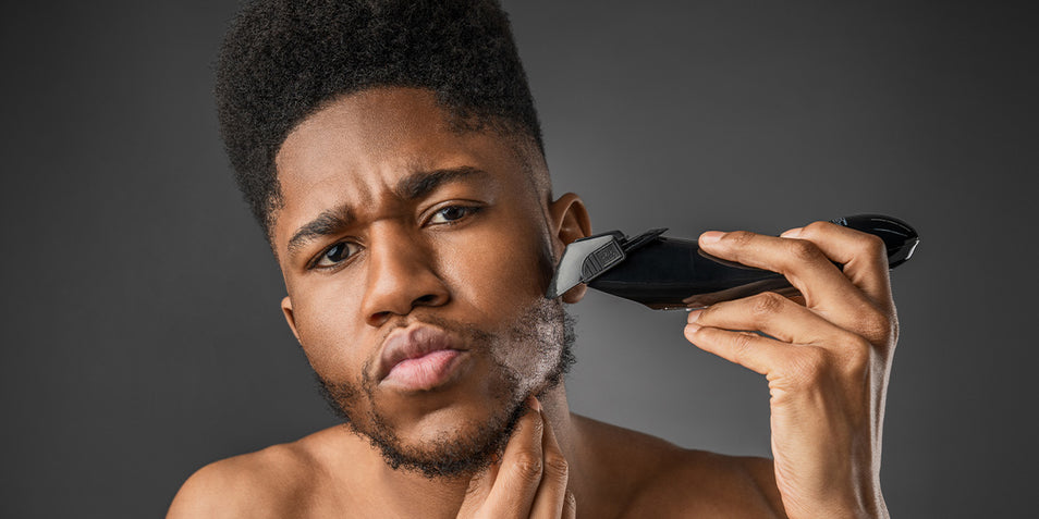 A black man using a beard trimmer